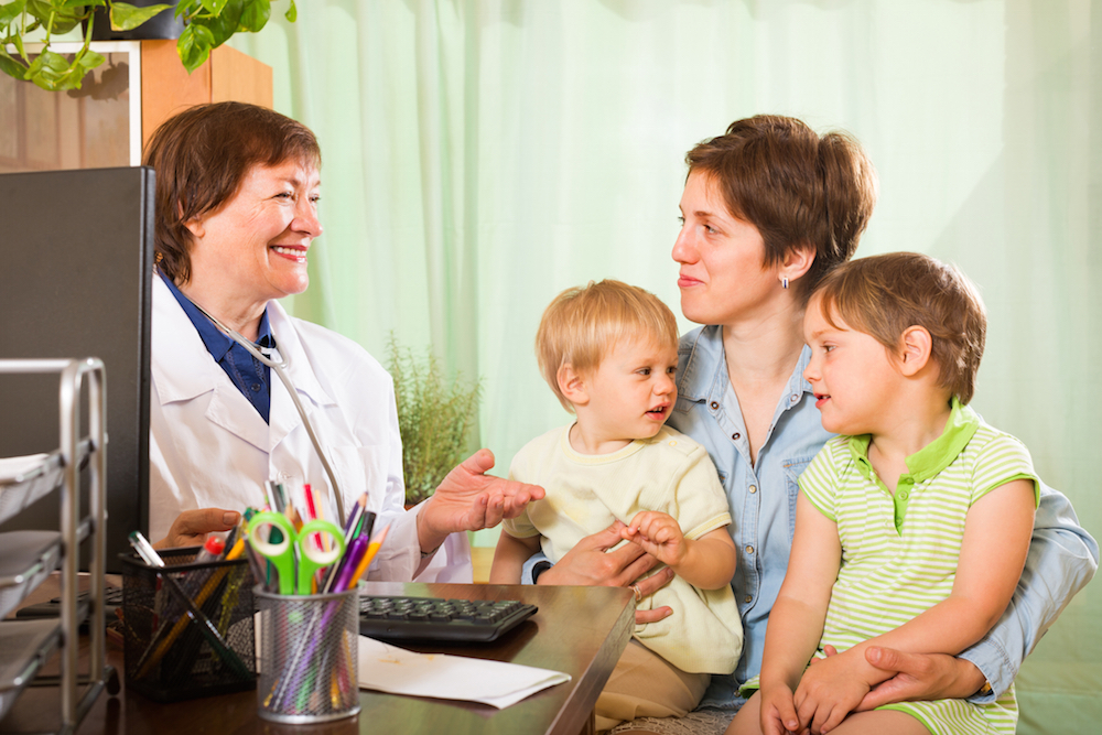 Mother with two kids on her lap talking to a doctor