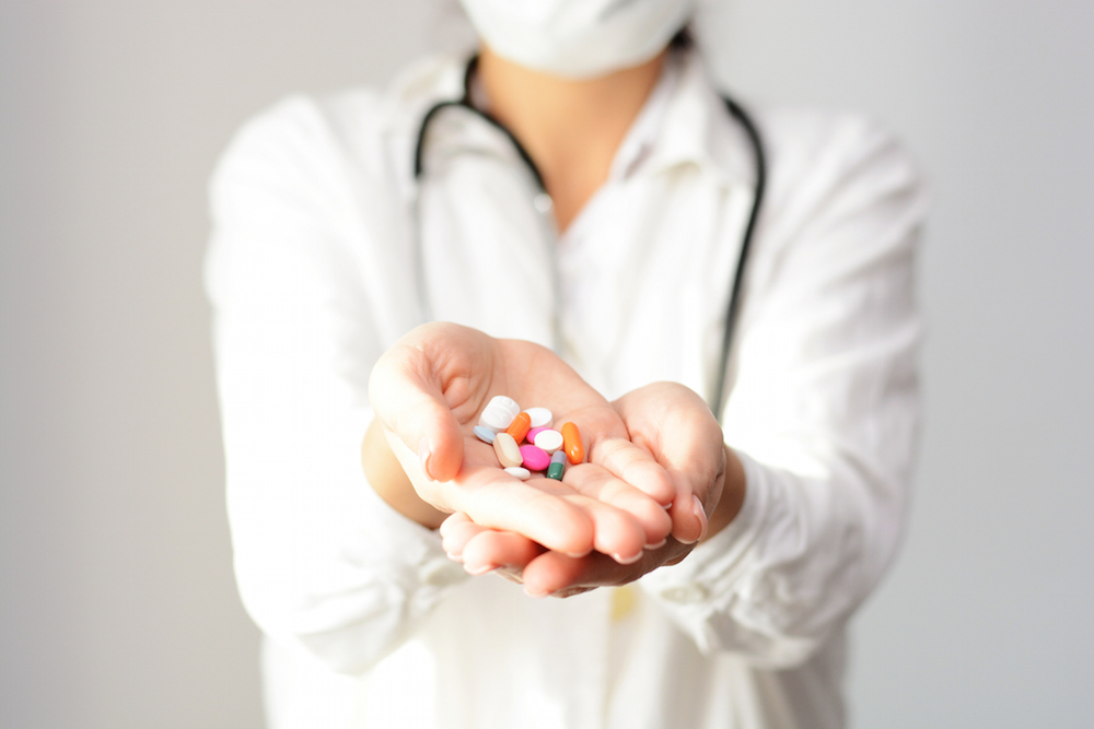 female doctor displaying a handful of tablets and pills in her palm