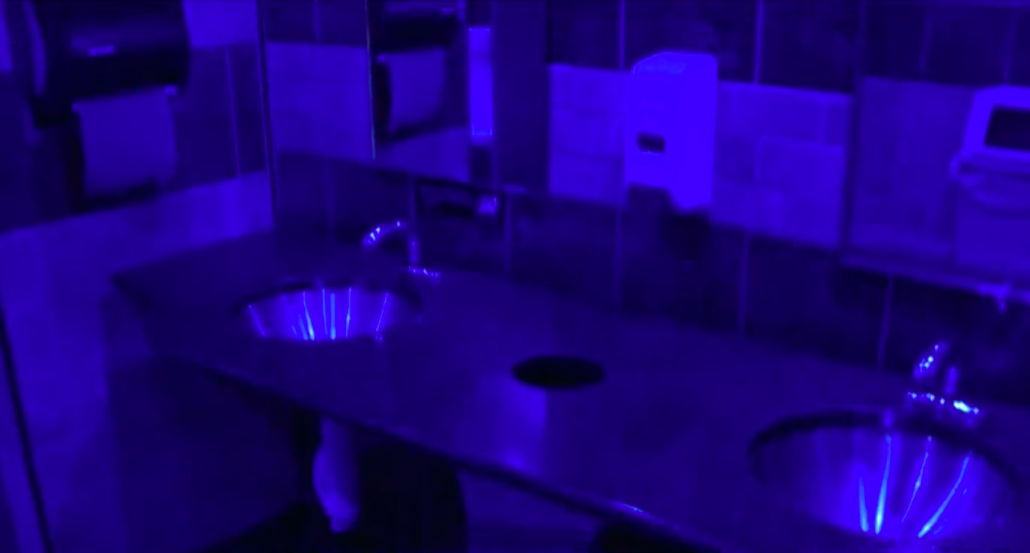 a gas station bathroom lit with blue bulbs