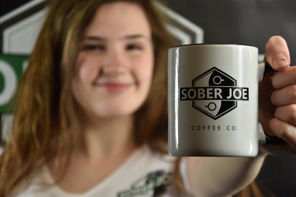a woman holding a mug that says Sober Joe