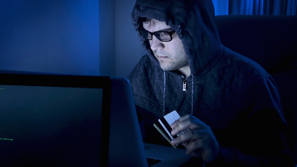 man in hoodie looking at laptop in the dark
