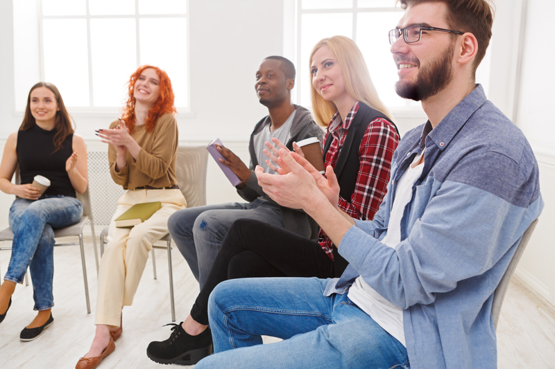 People on chairs in a meeting, clapping