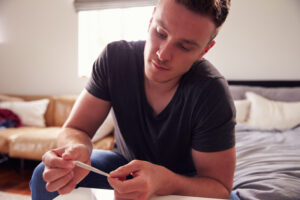 Young man holding marijuana joint, contemplating it.