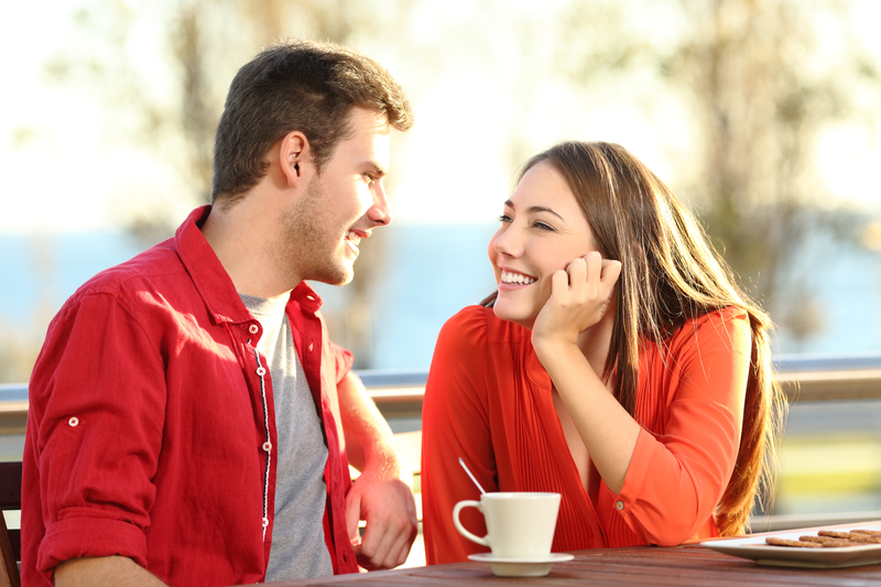 A man and woman sit together; the woman looks adoringly at the man