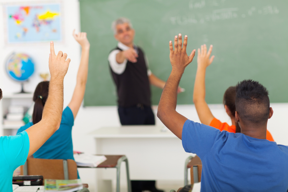 students raising their hands in a classroom
