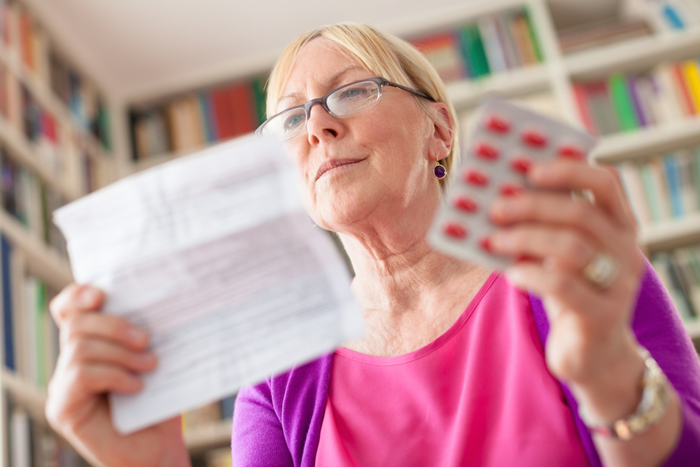 woman holding instructions and a packet of pills