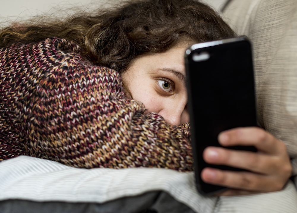 Teenage girl using a smartphone while laying in bed