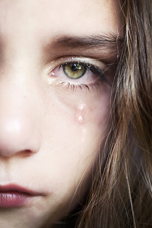 A woman's face with a tear falling down her cheek.