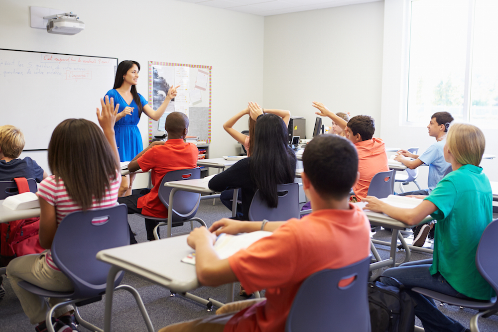 kids raising hands in classroom