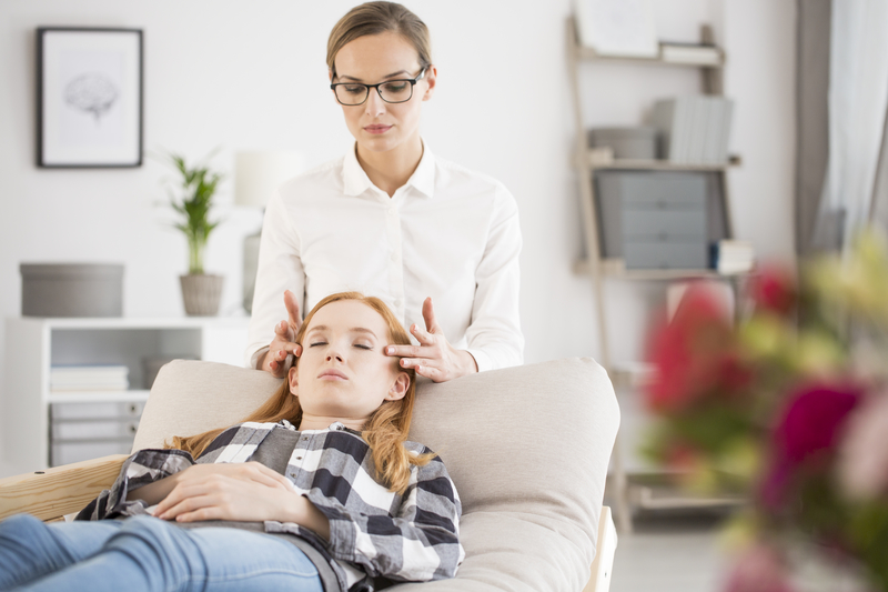 A woman is lying down, receiving temple massage from a clinician.