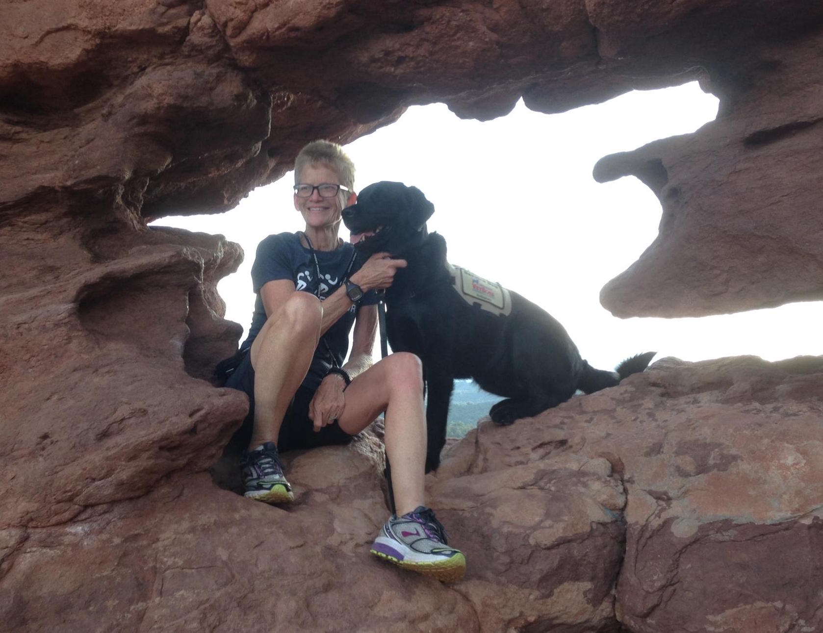 Gretchen Evans and her dog, Aura, sitting together on rocks.