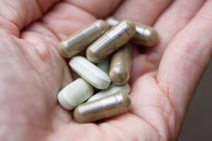 Close-up of hand holding herbal medicine capsules and tablets
