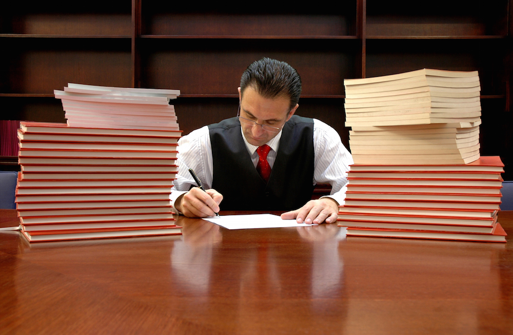 seated lawyer surrounded by stacks of documents