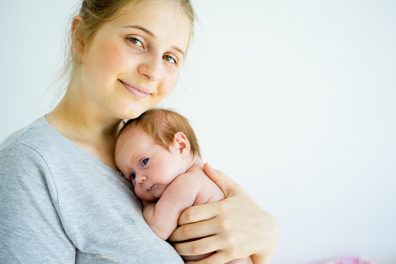Smiling mother holding newborn baby.