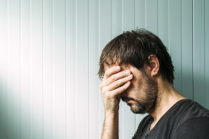 Man with hand over face, appears distressed.
