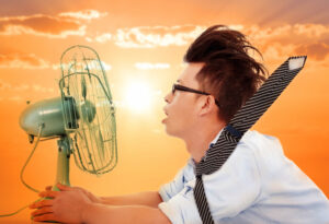 man sitting in front of a blaring fan on a hot day