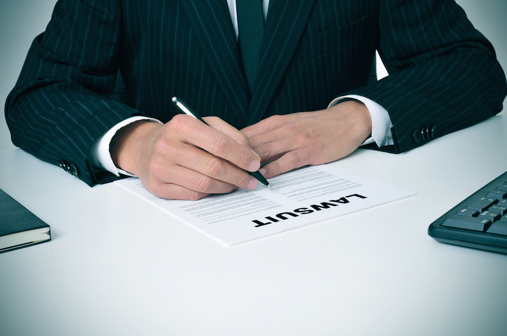 a lawyer signing a document that says lawsuit.