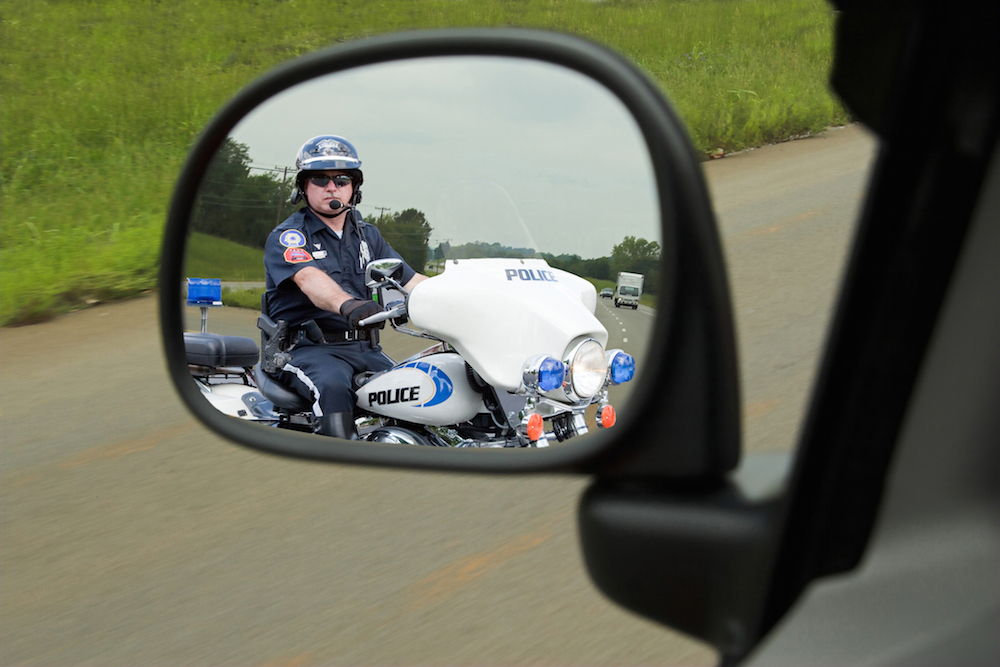 Police officer on his motorcycle pulling in behind a vehicle