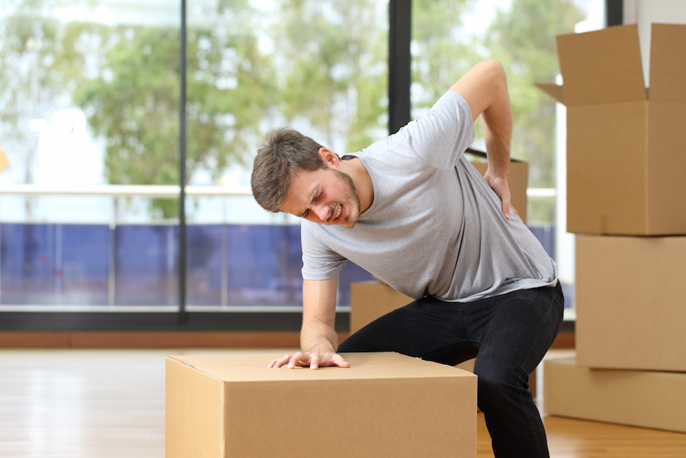 Man suffering back ache while moving boxes