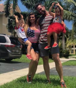Garren James, his wife, and their two children stand outside, smiling.