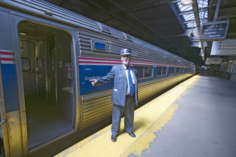 conductor standing at entrance of Amtrak train car