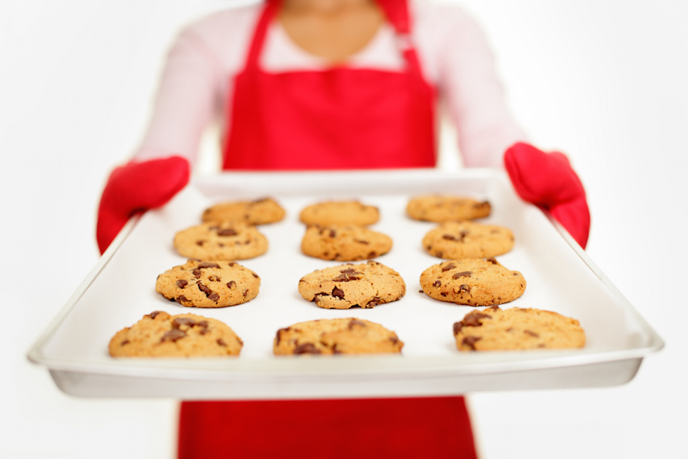 woman holding a tray of chocolate chip cookies