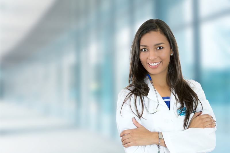 Smiling woman in lab coat with stethoscope.
