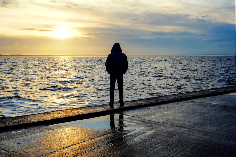 man standing on beach at sunset