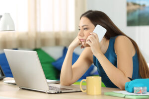 Woman talking on phone and looking at computer screen.