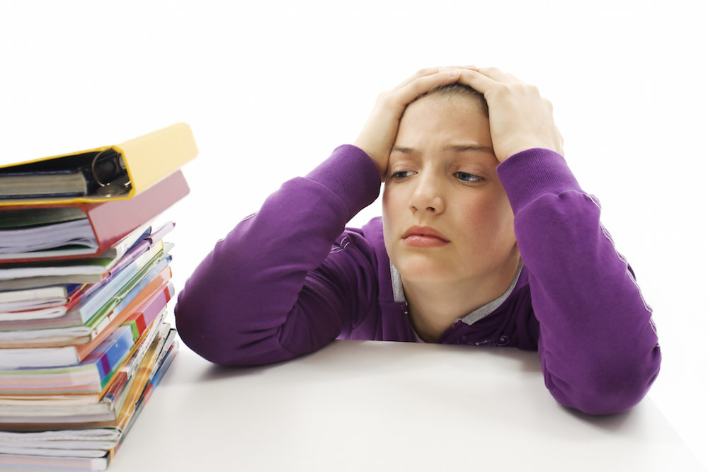 a frustrated kid staring at a pile of books.