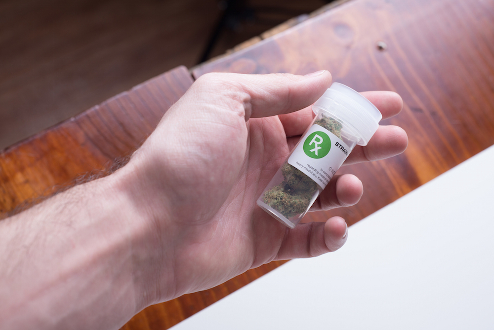 hand holding prescription bottle of medical cannabis