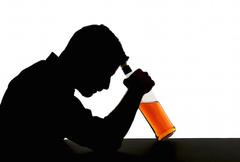 silhouette of a man holding a bottle of alcohol