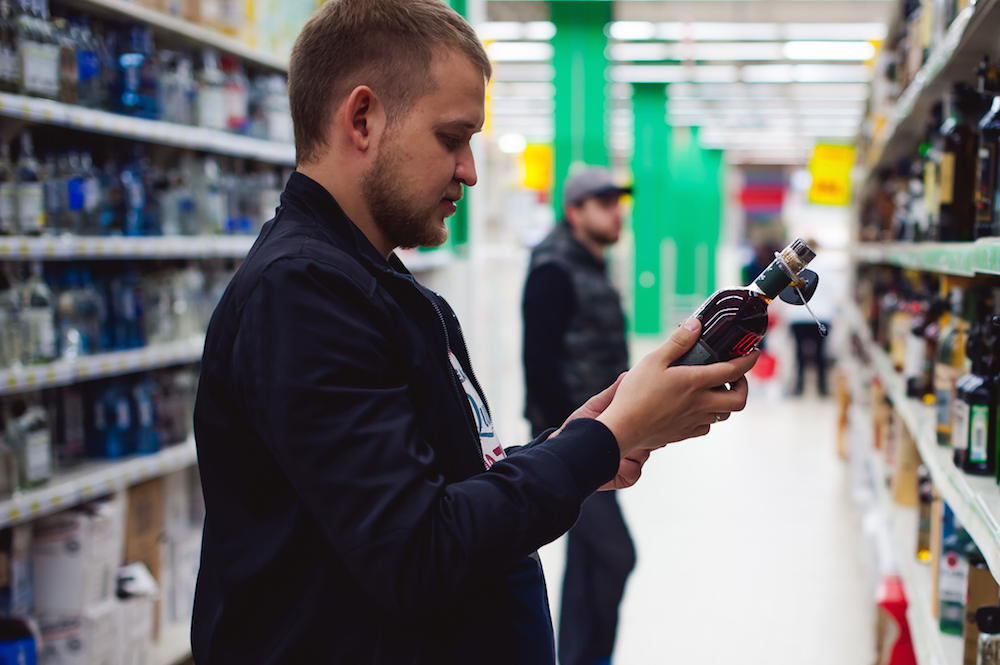 man examining bottle of alcohol in store