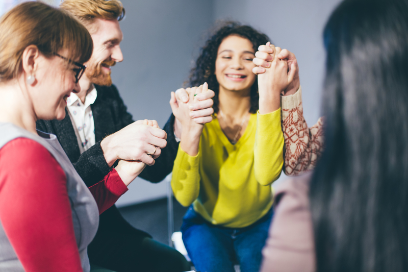 happy people holding hands in a group therapy setting.
