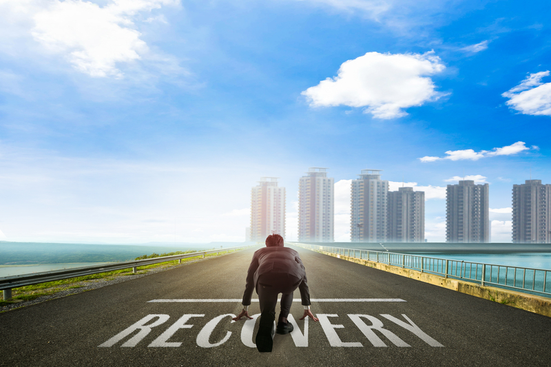 Businessman ready to run toward the city on a road with "Recovery" written on it.