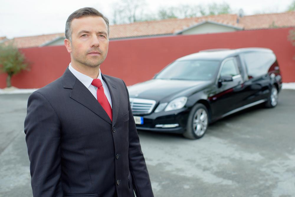 funeral directors standing in front of a hearse