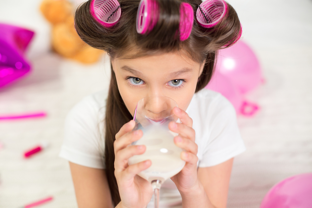 child drinking out of wine glass