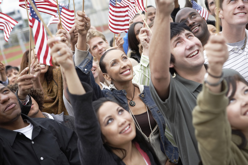 People smiling holding American flags, voting for drug policy at midterm elections.