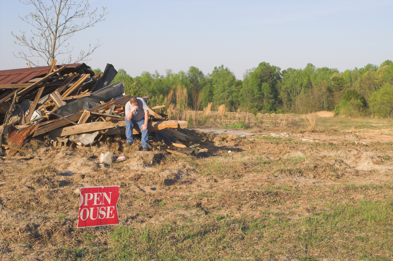 A man sits on what remains of his house, head in hands. Climate change mental health