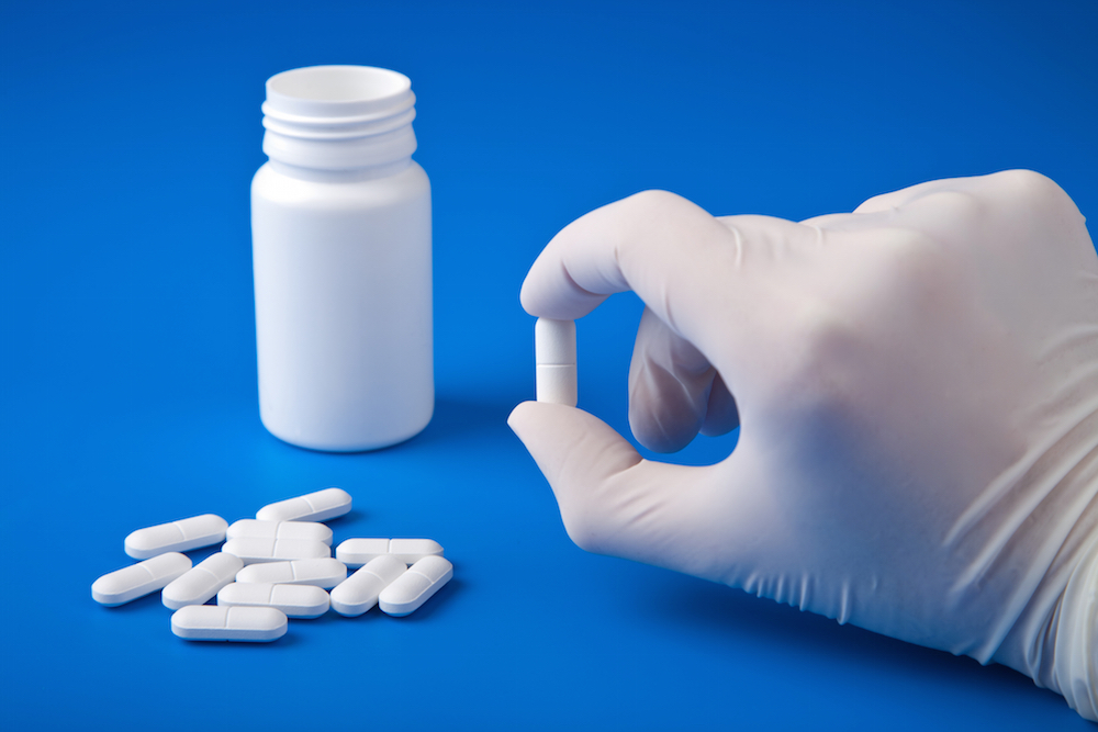 gloved hand holding pill