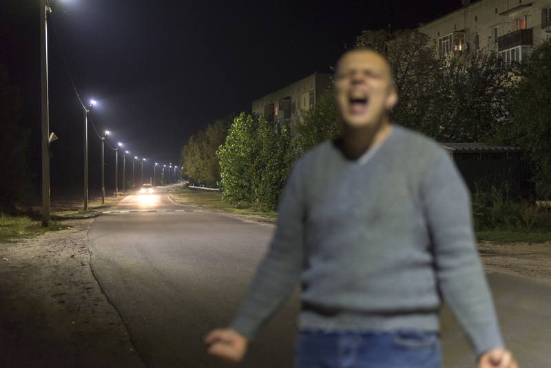 Blurred image of a man screaming at night on an empty street. Buying drugs on Christmas, dope dealer