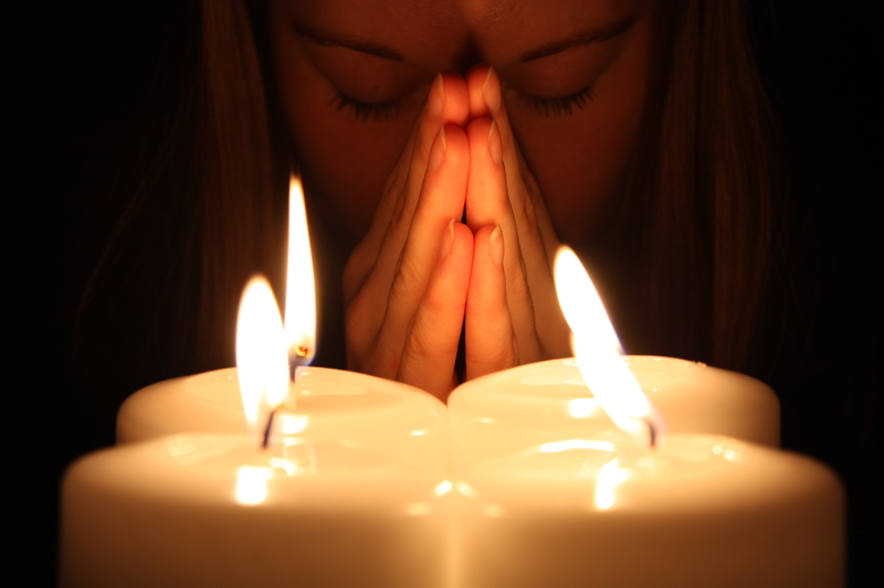 Woman praying over candles, deepening commitment to recovery