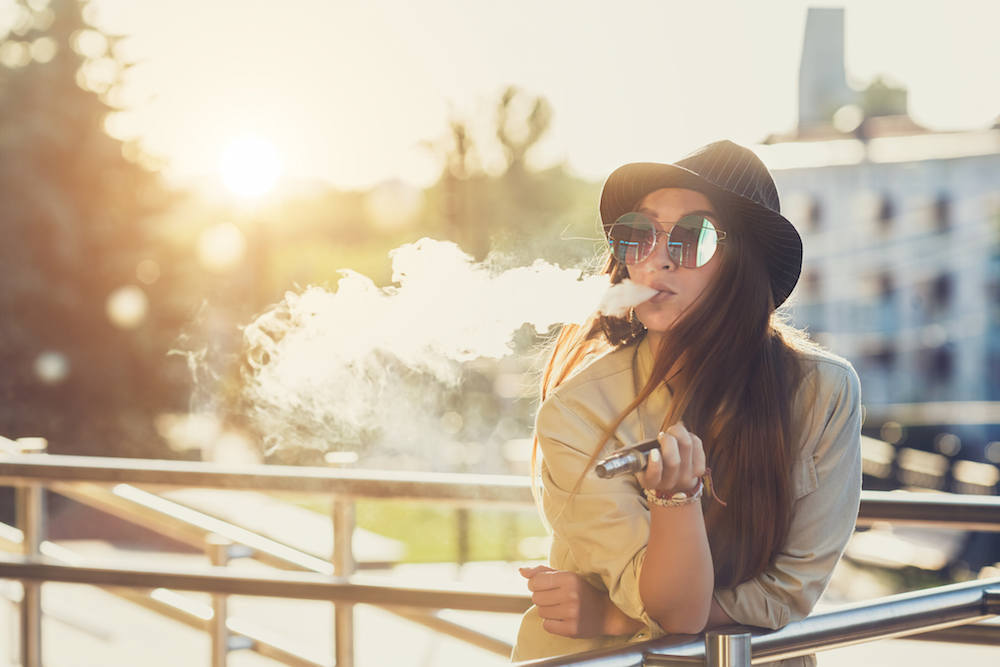 teen girl vaping  an e-cig outside