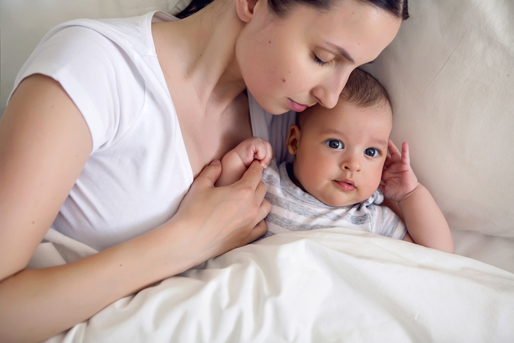 A mother laying beside her newborn baby who was born dependent on opioids
