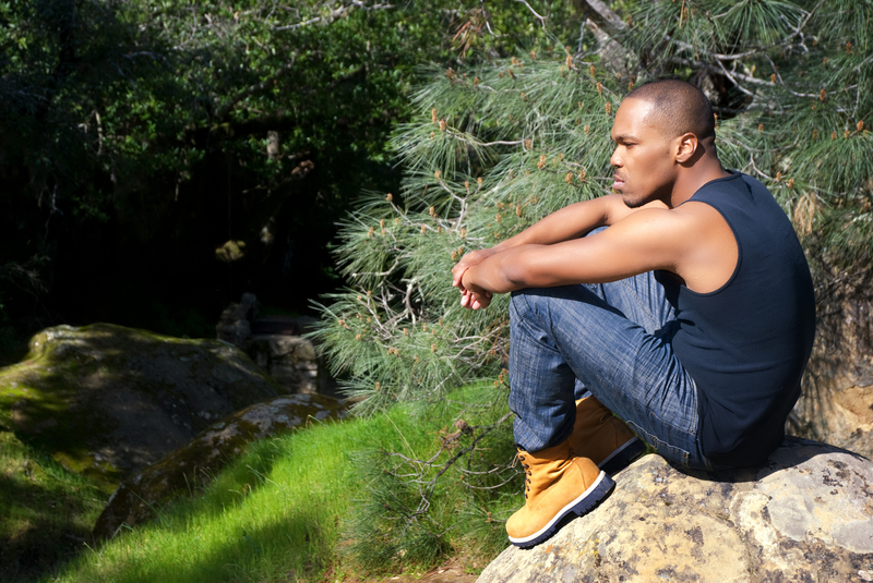 Man sitting on a rock, contemplating moving in sobriety, geographic