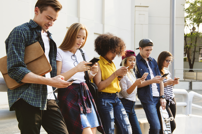 Millennials using smartphones outdoors together