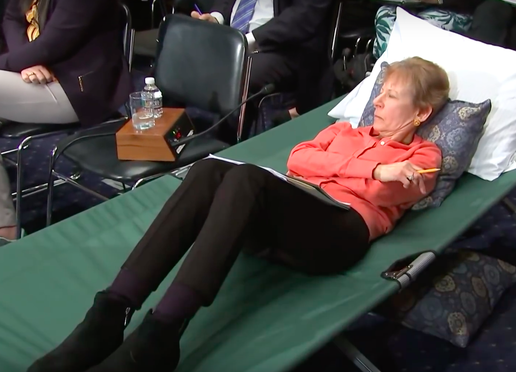 woman on cot testifying about chronic pain in front of Congress