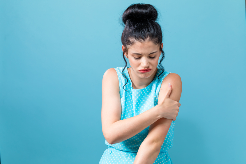 Woman looking frustrated and scratching upper arm, ringworm and alcoholism