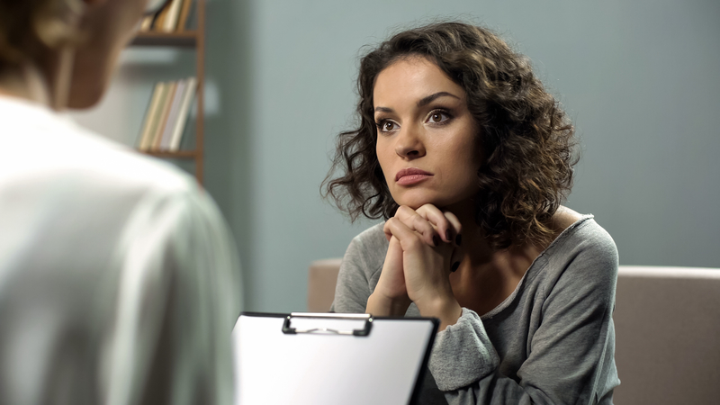 Thoughtful woman with doctor or therapist, getting evidence-based addiction treatment
