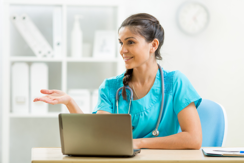 Clinician sits at desk with computer, smiling while using ZenCharts medical records